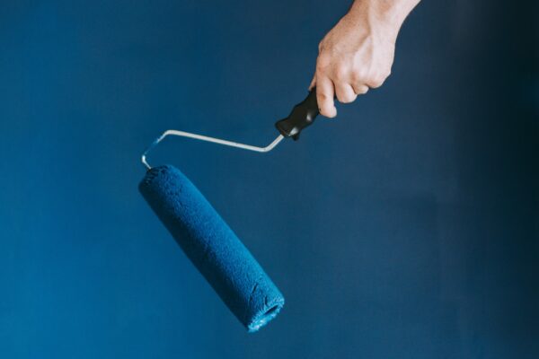 A closeup shot of a female using paint rollers with the color blue